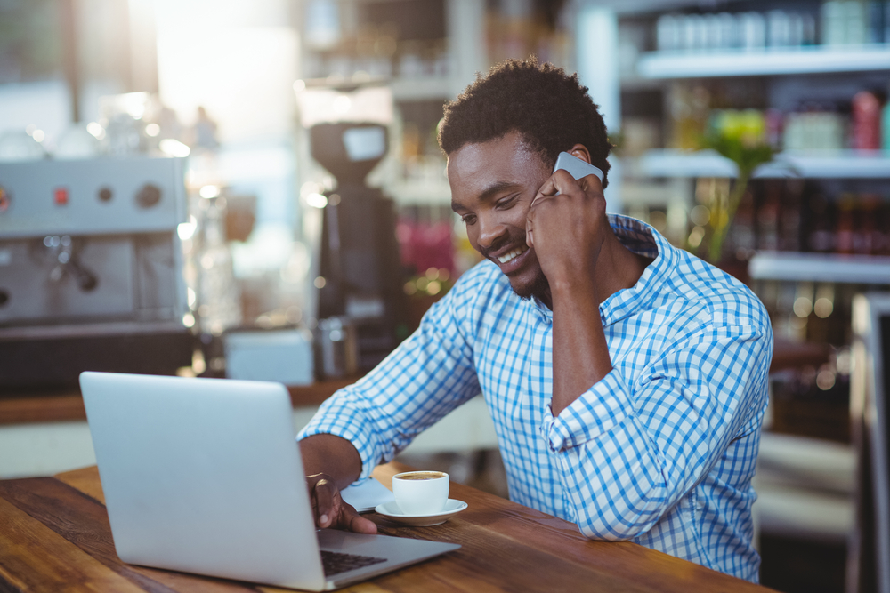 Smiling man talking on mobile phone in cafe